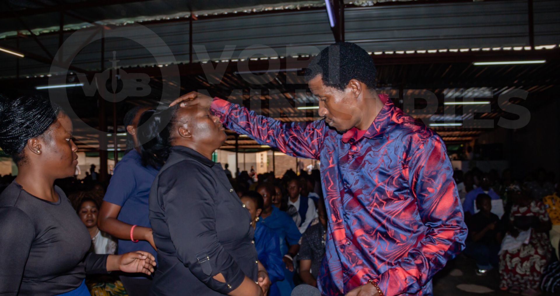 Prophet Promise praying for a member of the congregation during a VOBI service